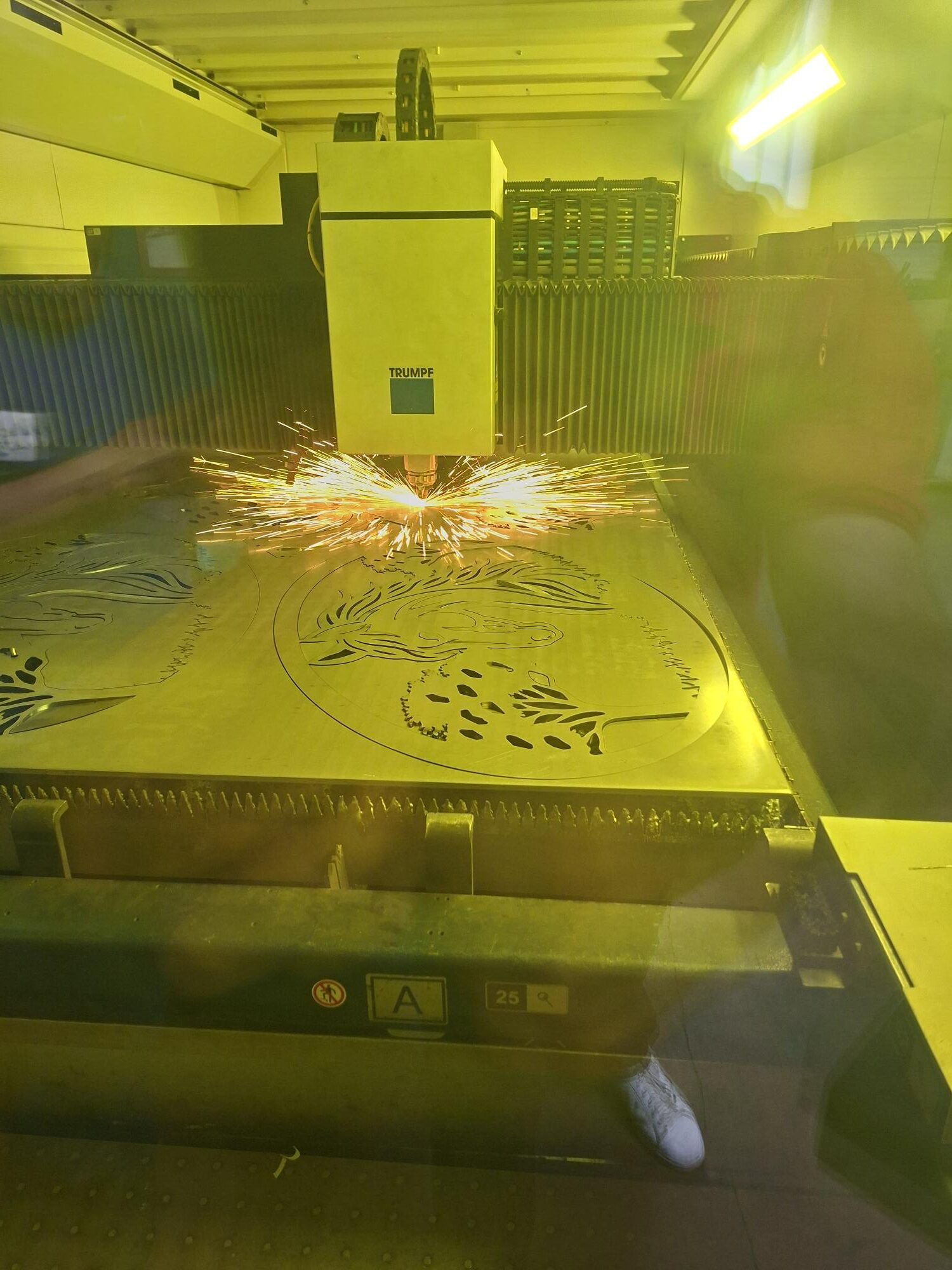 Découpe laser en cours d'une tôle d'inox avec gerbe d'étincelles